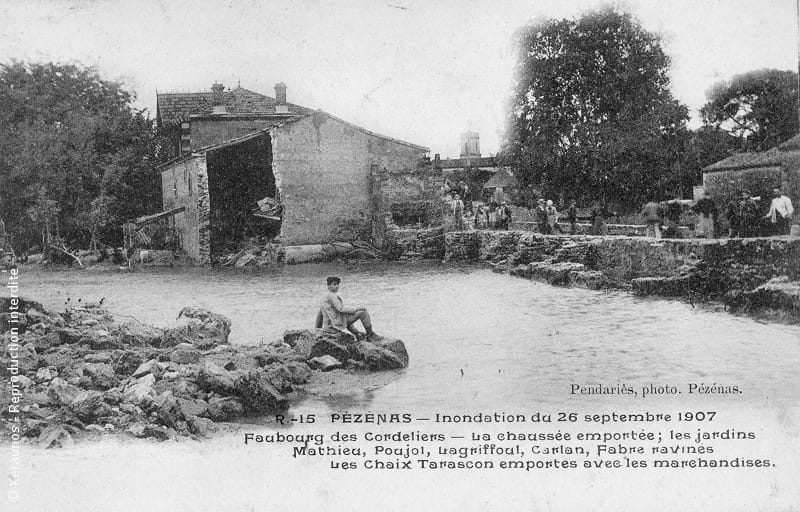 PÉZENAS (Hérault) - Crue de la Peyne du 26 septembre 1907. Faubourg des Cordeliers. Aperçu de l'avenue Carion-Nizas en direction du centre-ville. Au premier plan, les berges de la Peyne. A l'arrière plan, le campanile de l'église collégiale Sain-Jean. © Keraunos