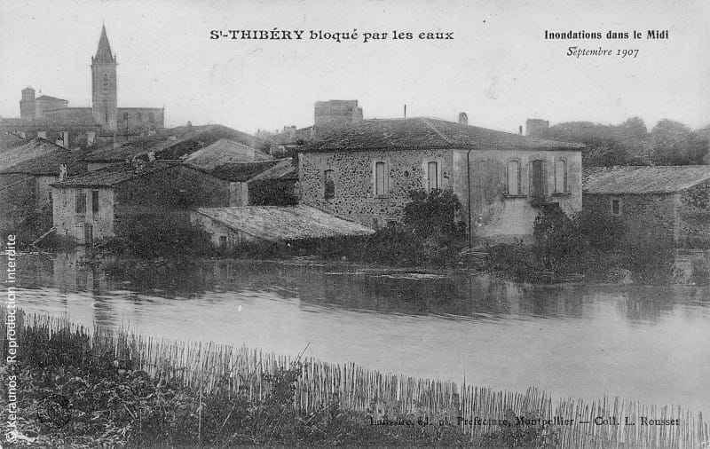 SAINT-THIBÉRY (Hérault) - Crues des 25-30 septembre 1907 (Thongue et Hérault). Vue d'ensemble de la commune dans le périmètre du boulevard des Ecoles. Au fond, le clocher de l'église abbatiale. © Keraunos