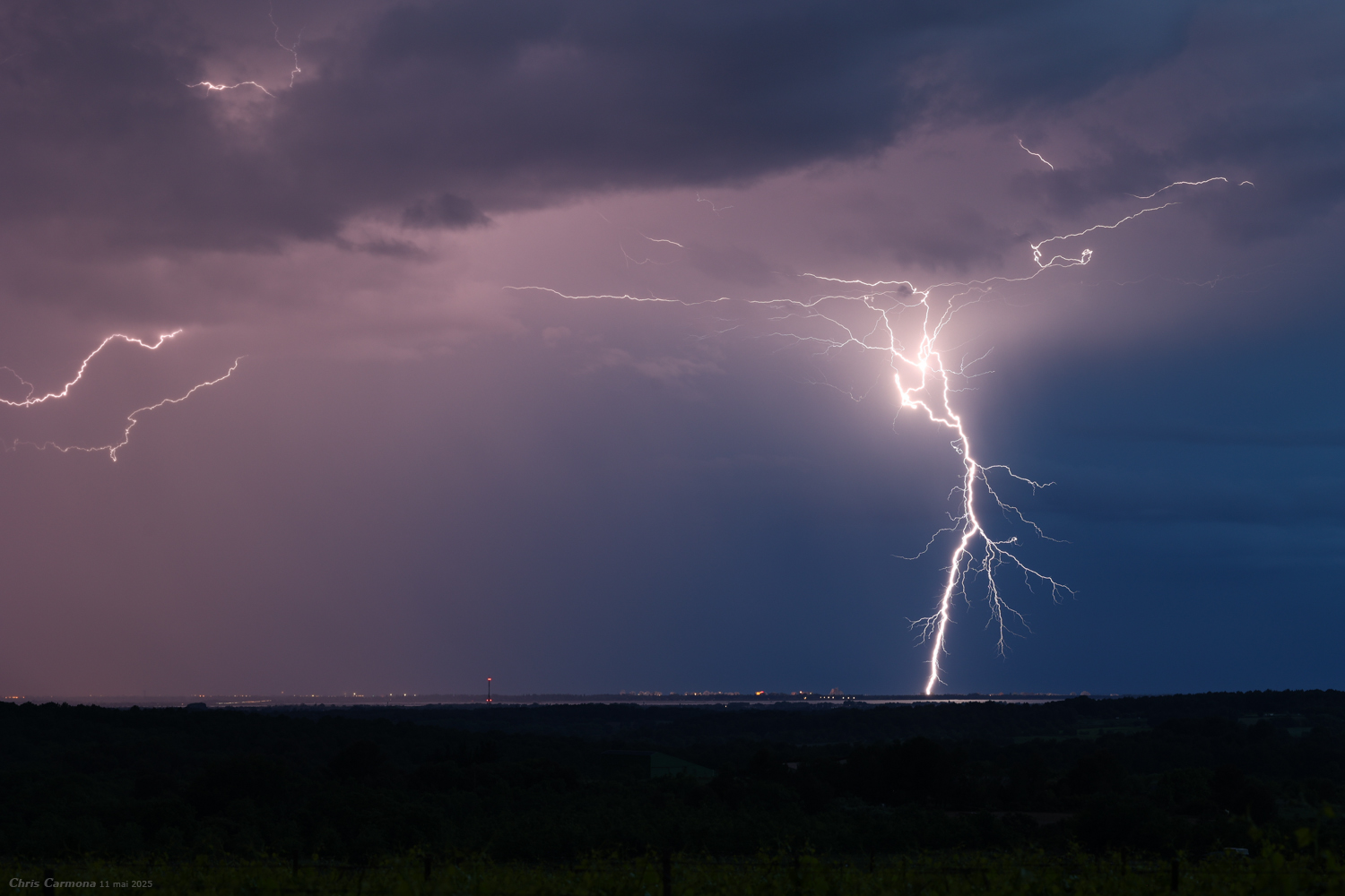 Impact de foudre à l'arrière de la ligne orageuse sur le Camargue. L'impact tombe dans le panache stratiforme sur La Grande-Motte à environ 10km des noyaux diluviens. Photographié depuis l'intérieur des terres vers Restinclières (34). - 11/05/2025 21:22 - Christian Carmona