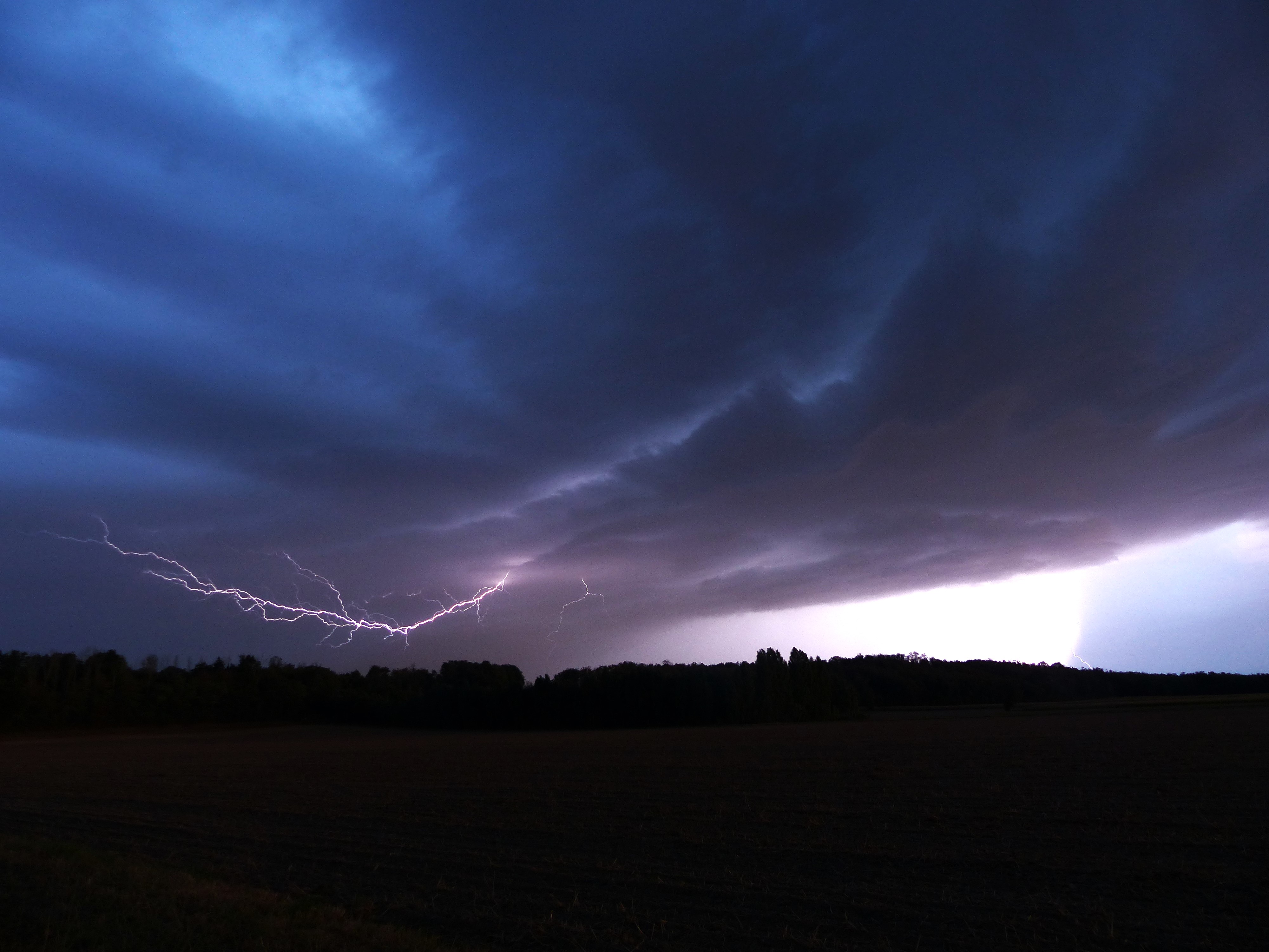 Bonsoir, 
ma premiére trés belle photo d'éclair! 
Bel éclair intra nuage lors d'un orage sur le plateau de la Dombes ce samedi 26/08 vers 21h00, la vue est en direction du sud, vers l'agglomération Lyonnaise.
Un autre éclair touchant le sol à droite illumine la partie pluvieuse, le contraste est joli à l'œil. 
Il y a un post-traitement sur les lumières mais pas sur les couleurs, le ciel étant réellement aussi irréel en réalité que sur la photo! 
Pose longue de 2 seconde. 
Travail personnel, publié sous Licence libre CC-BY-NC
Cordialement,
B.L - 26/08/2023 21:00 - Benoît Lautier