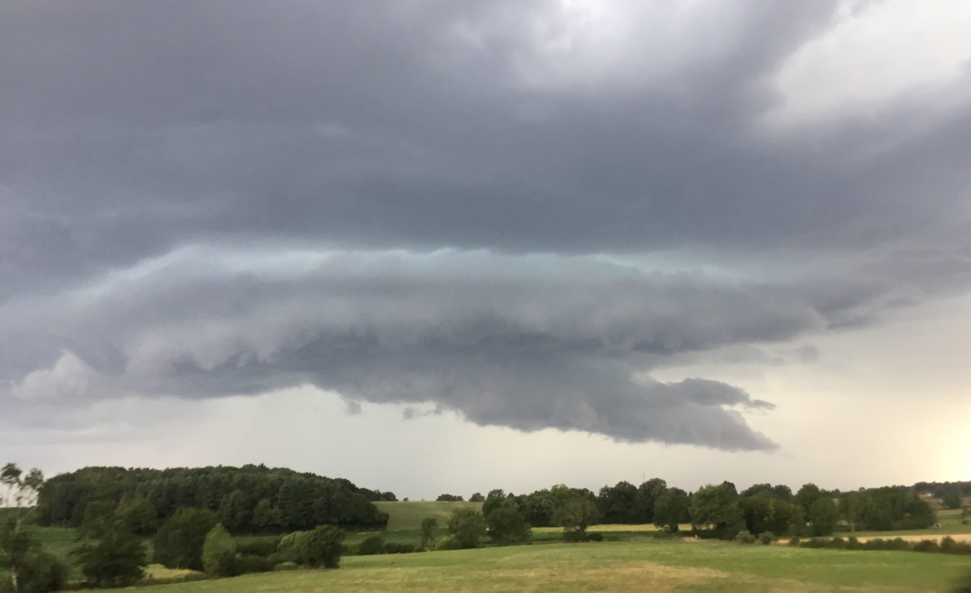Une base nuageuse menançante avec semble-t-il un nuage mur, approche du rebord jurassien depuis la Bresse. Environs de Bény. - 15/07/2018 18:29 - Olivier Julian